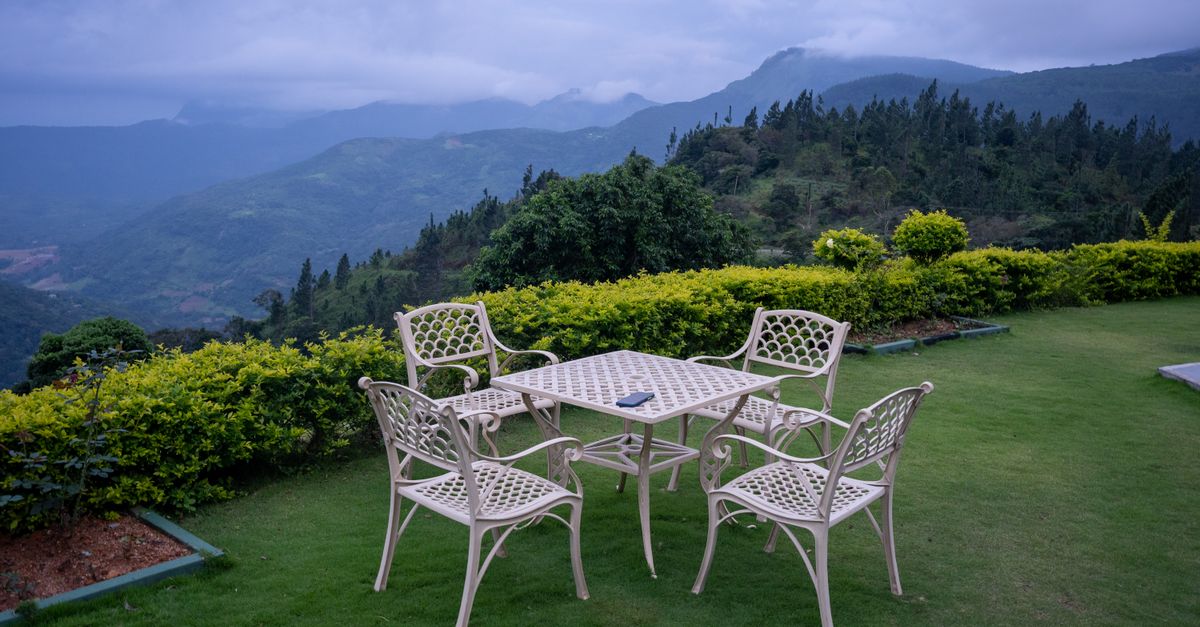 Outdoor patio set overlooking lush mountains under a cloudy sky.